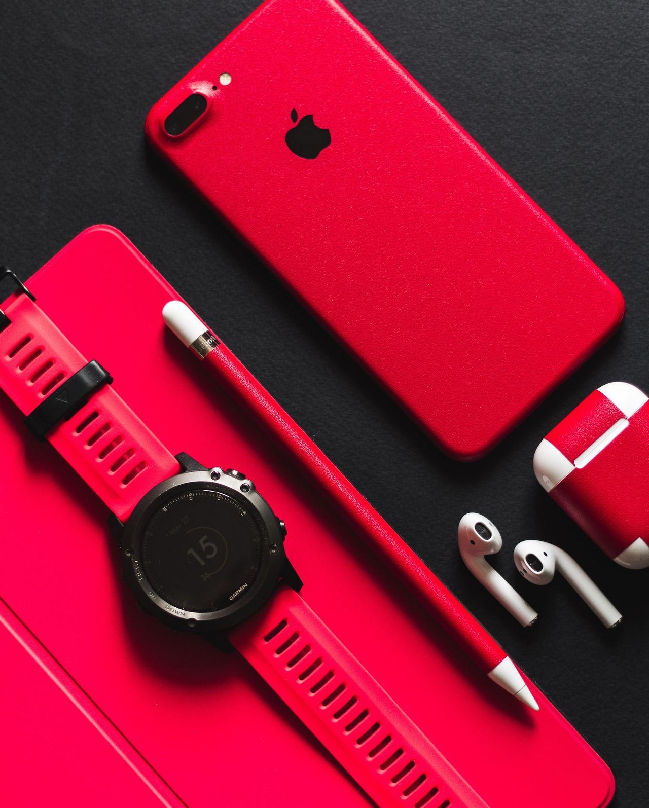 smartwatch, stylus, AirPods, and product red iPhone 7 on black surface